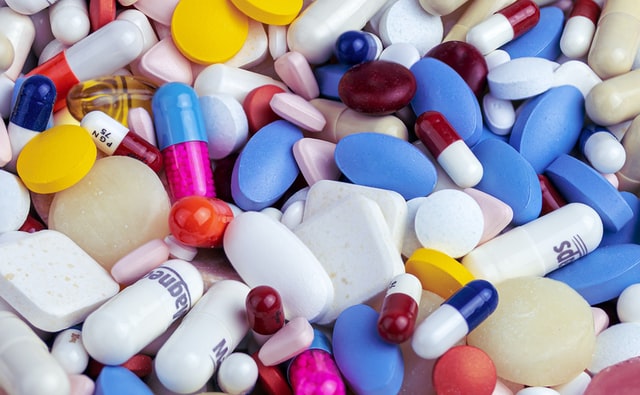 Pilha de remédios coloridos em forma de comprimido.