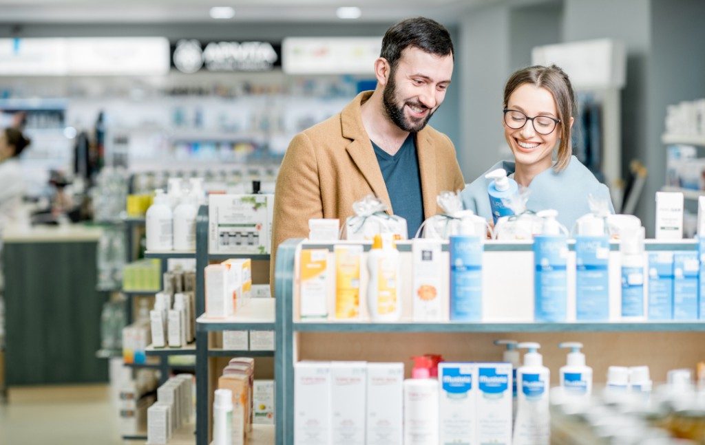 casal feliz escolhendo os produtos numa gondola de farmácia