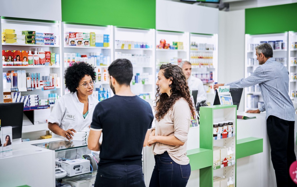 farmacêutica passando orientações a clientes no balcão da farmácia